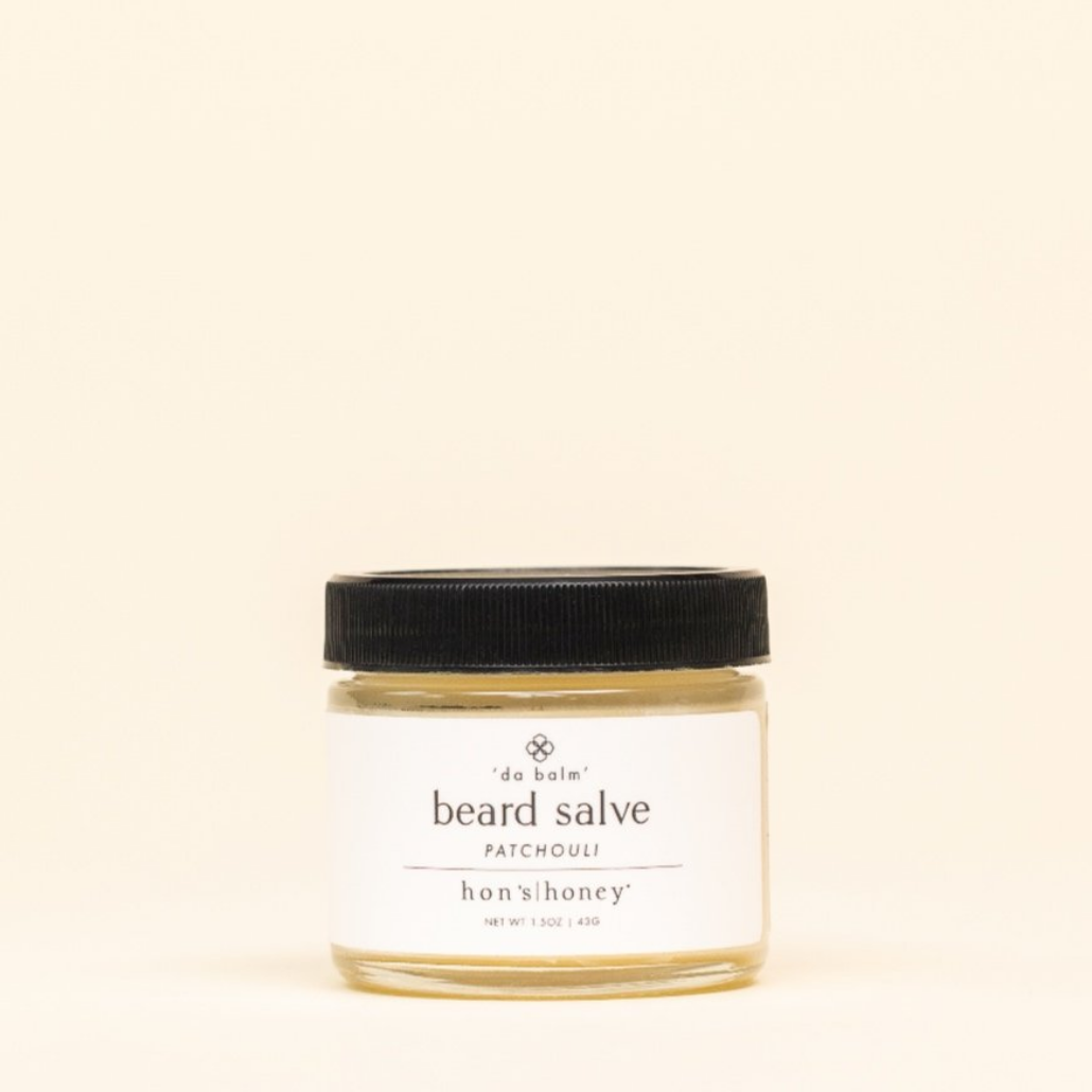 Jar of beard salve with a black lid on a beige background