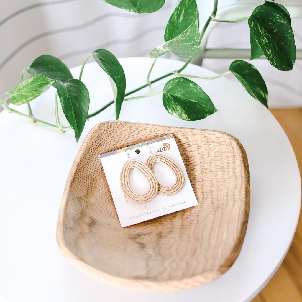 Pair of tan woven hoop earrings on a white card with &