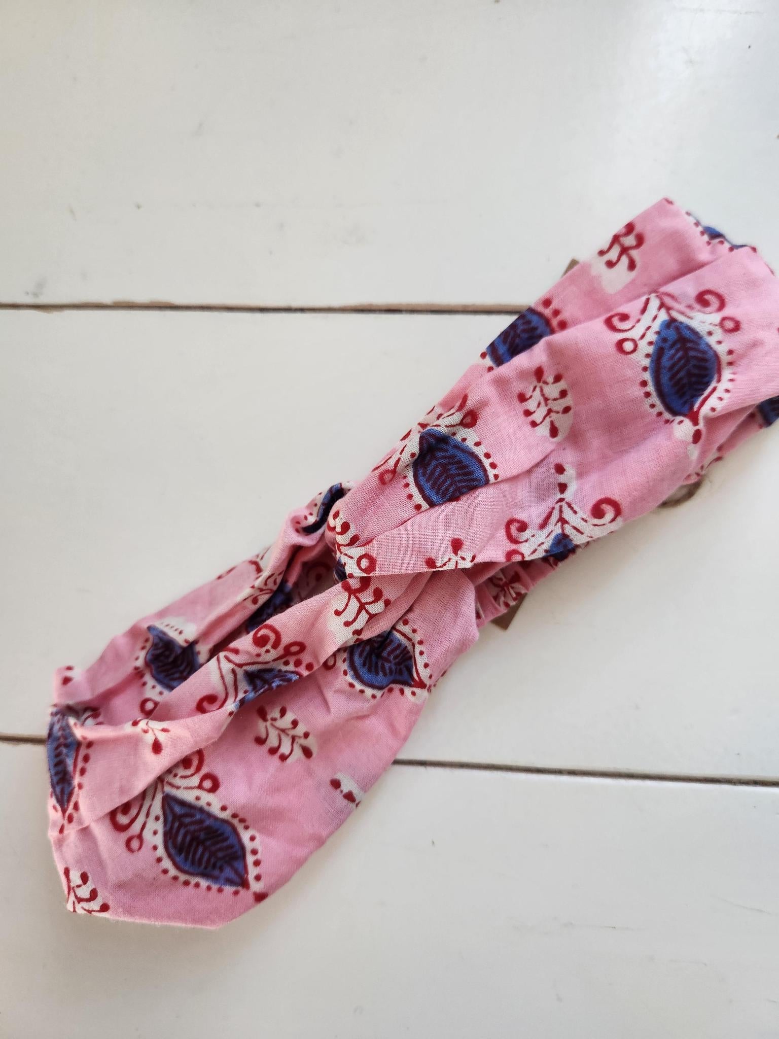 Pink headband with blue and red patterns on a white wooden surface