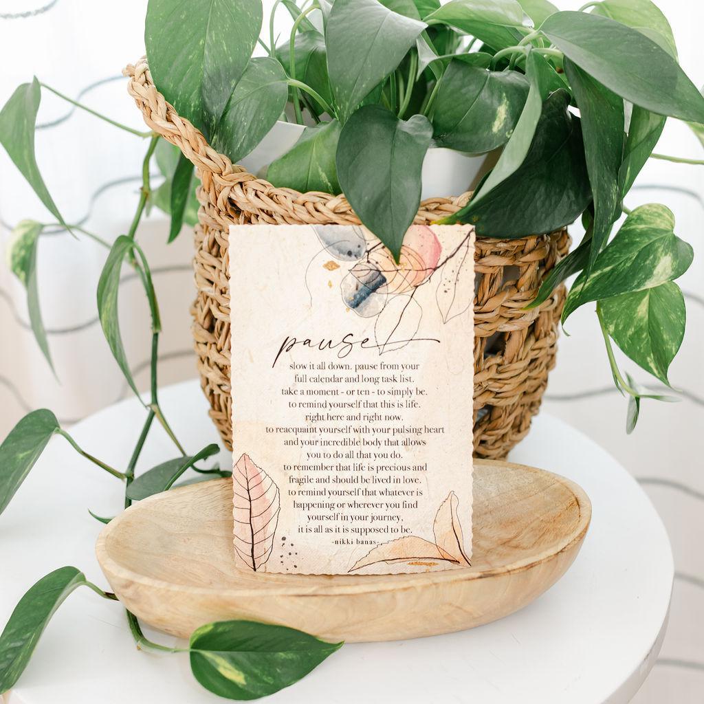 Large magnet card with text and leaf design in front of a potted plant on a white surface
