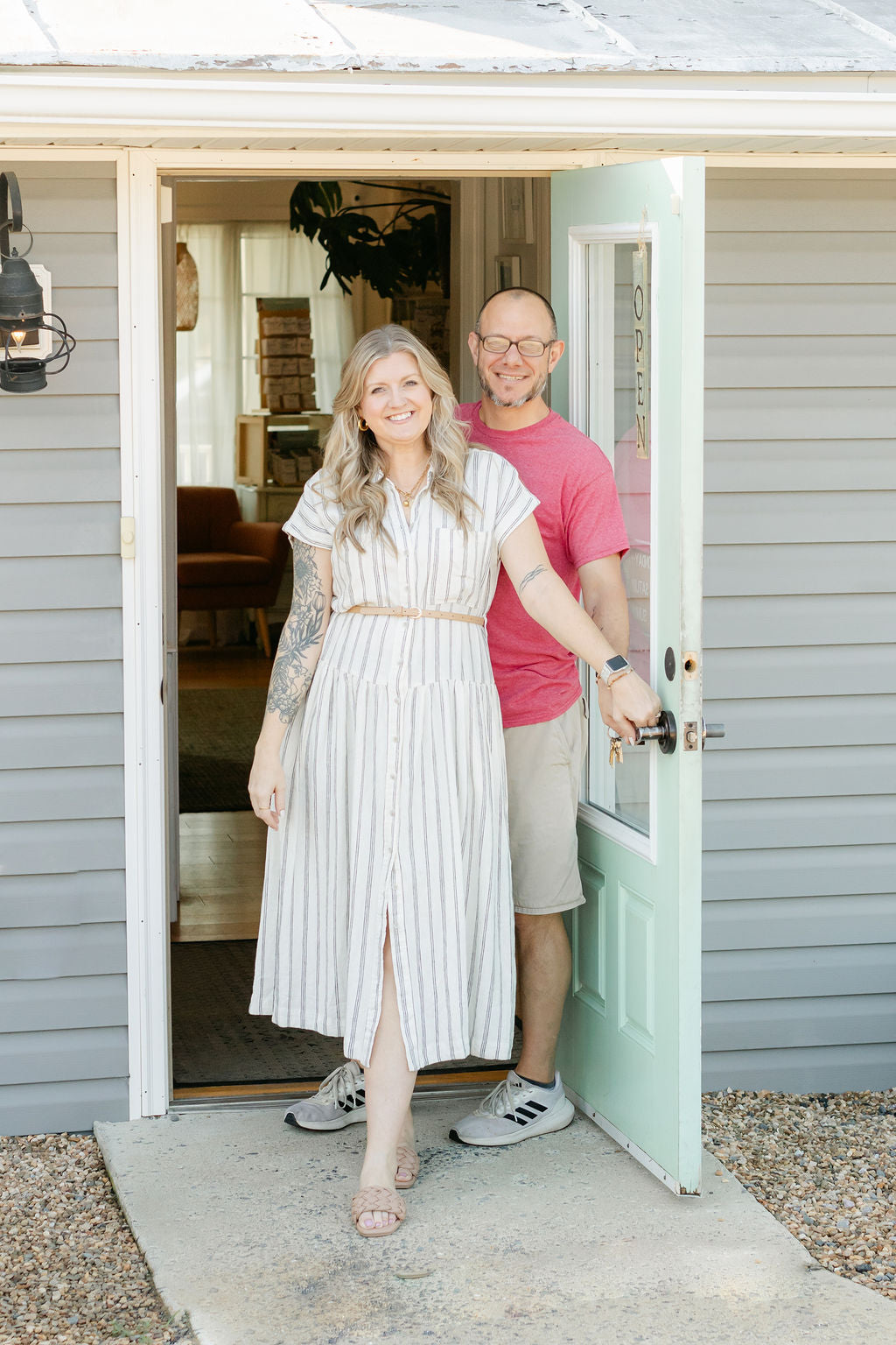 Man and woman standing in a doorway of a shop, smiling.