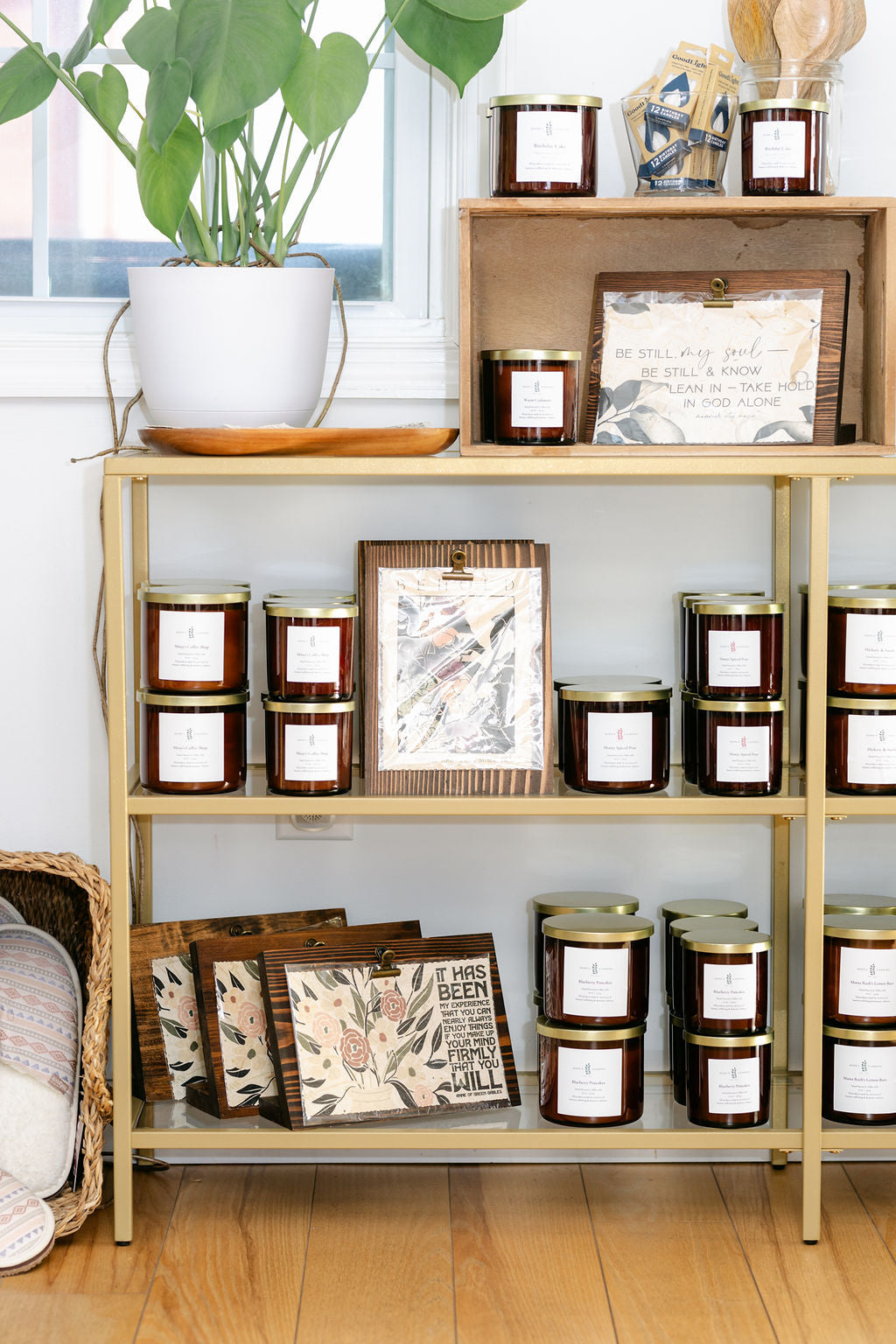Gold shelf with candles and framed pictures in a store setting
