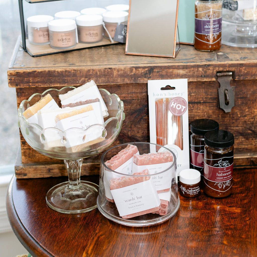 Assorted products including jars of soap and honey on a wooden surface