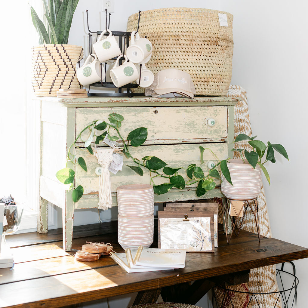 Decorative setup with a wooden dresser, plants, and wicker baskets in a shop setting.