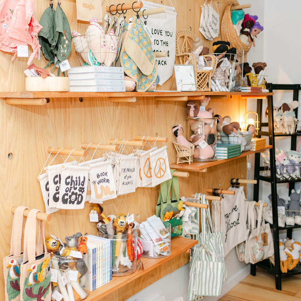 Wooden shelves with baby clothes, toys, and decorative items in a store setting.
