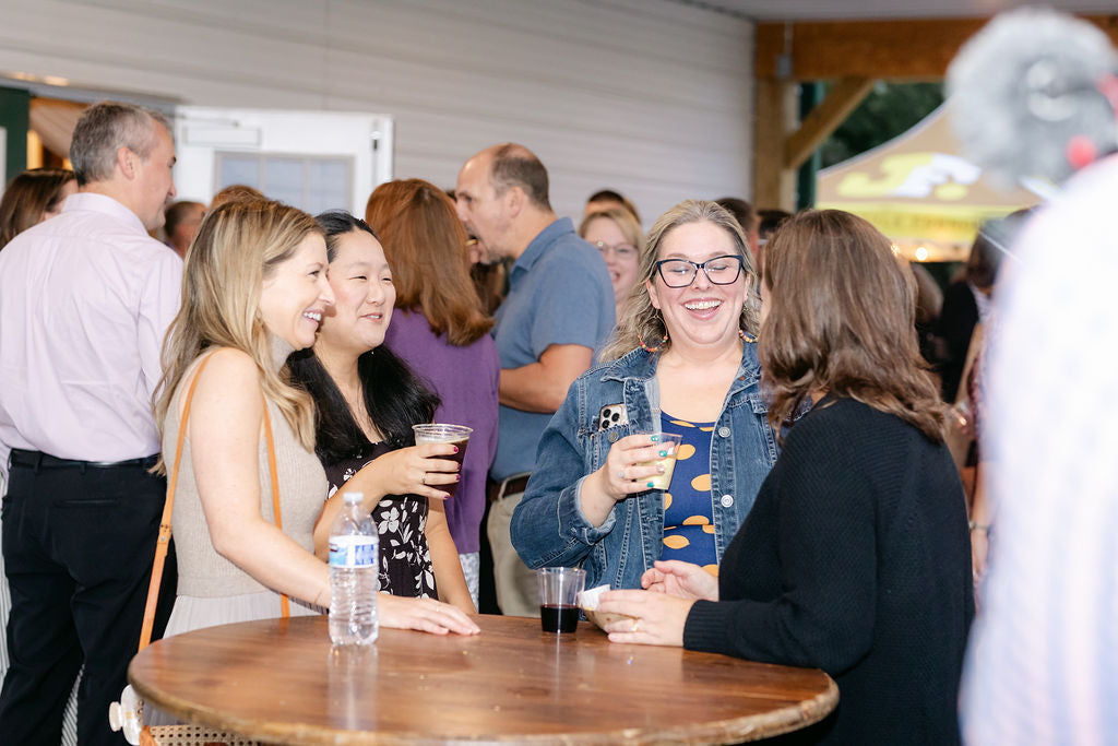 People socializing at an outdoor event with drinks and a casual atmosphere.