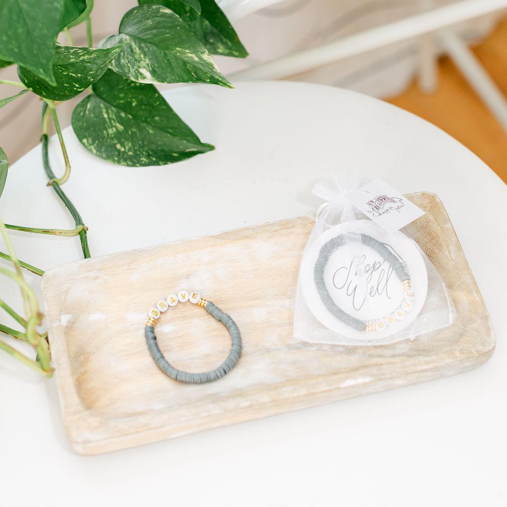 A pair of dark grey bracelets saying &