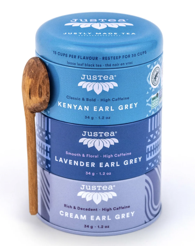 A tin container with three compartments labeled Kenyan Earl Grey, Lavender Earl Grey, and Cream Earl Grey, accompanied by a wooden spoon.