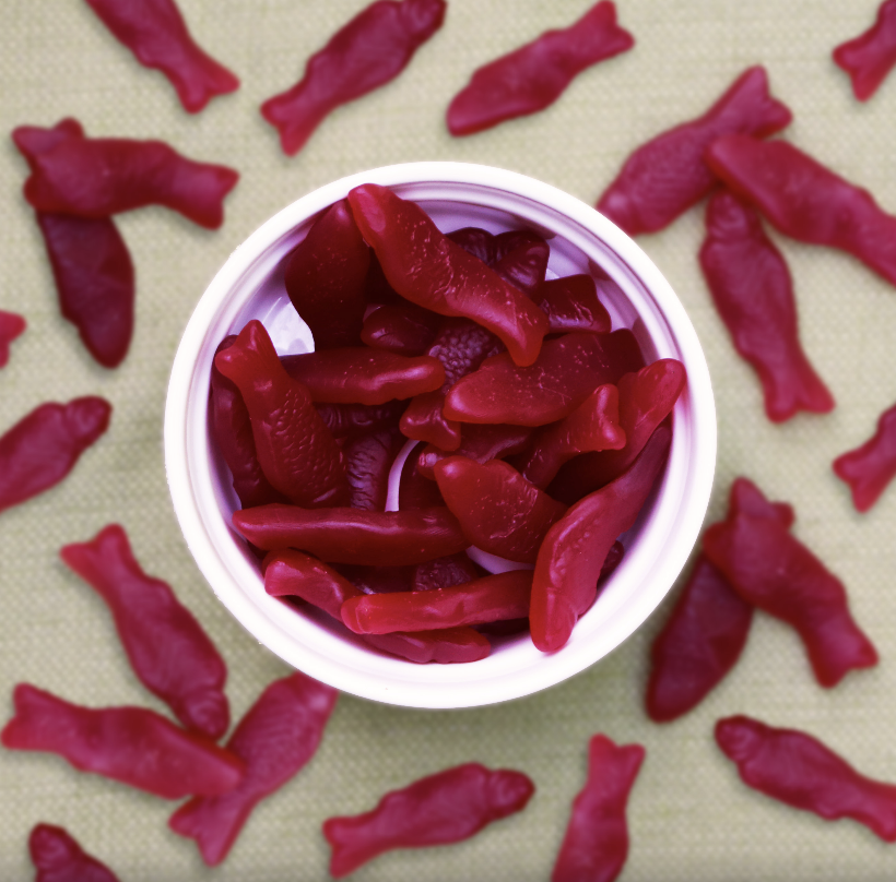A container with raspberry gummy fish in a white bowl