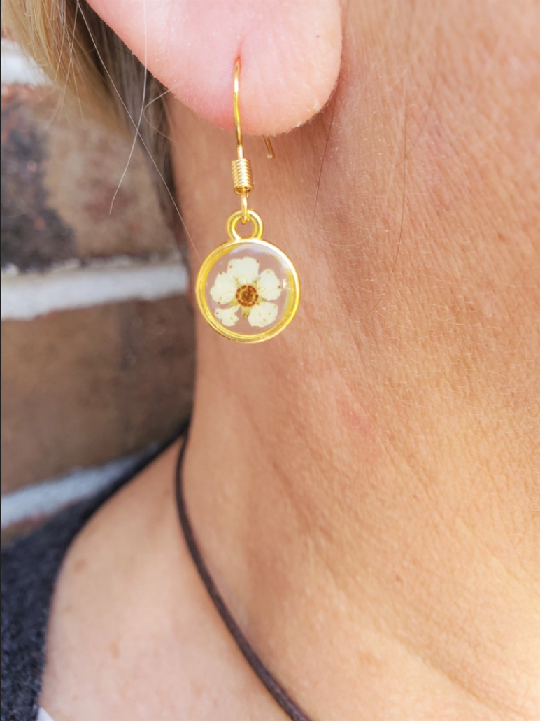 A teardrop-shaped earring with gold-plated, nickel-free, and hypoallergenic w/ white lower buds in a clear resin.