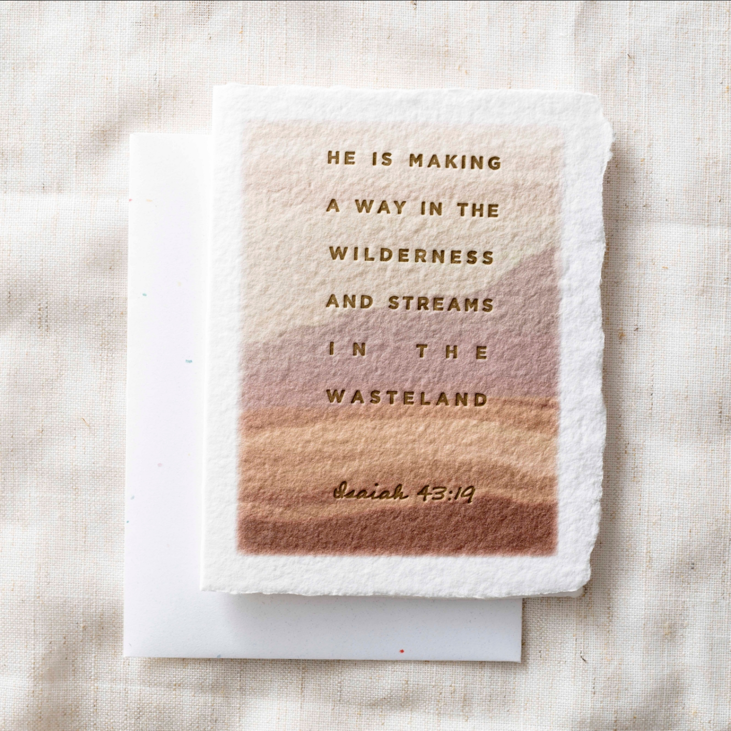 A square handmade paper card with rough edges featuring a warm gradient from cream to tan and brown, printed with the text &