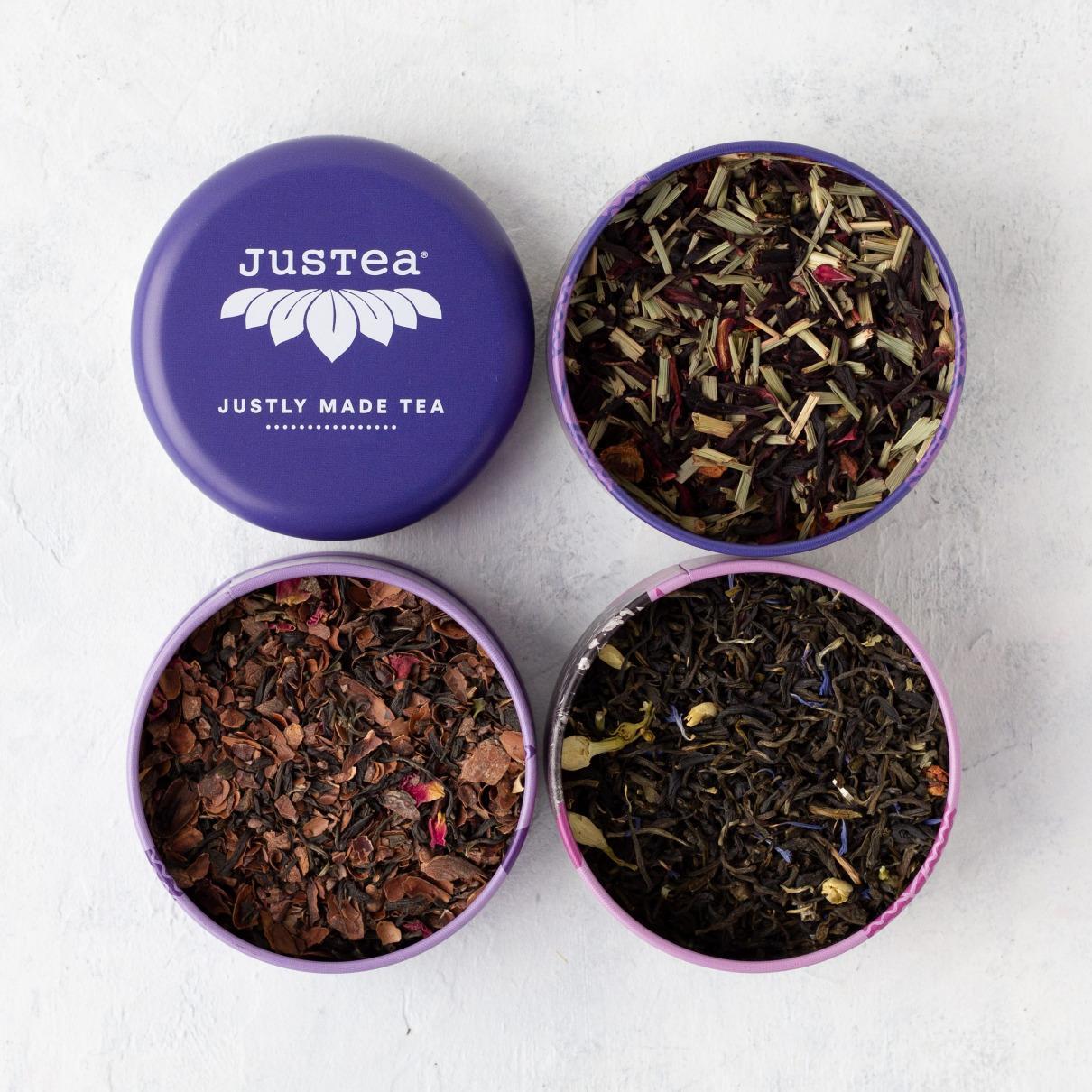 Top view of three tins of loose leaf tea. The purple lid says justea, justly made tea.