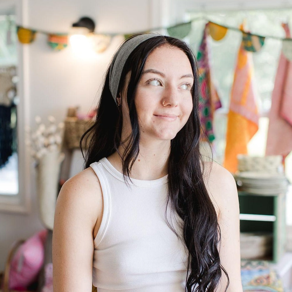 Young woman looking away from the camera wearing a gray headband in her dark hair.
