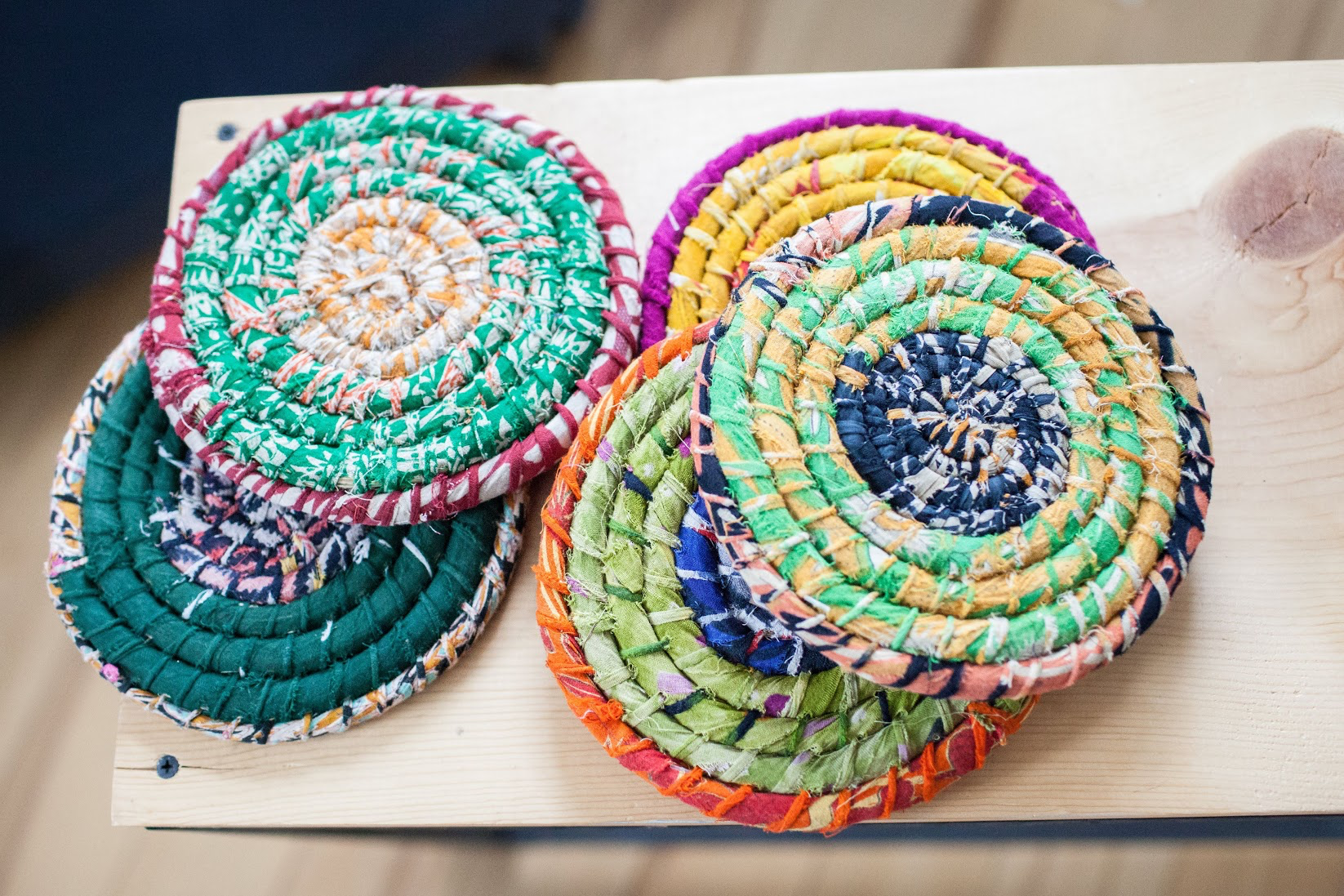A selection of colorful trivets on a wooden board.