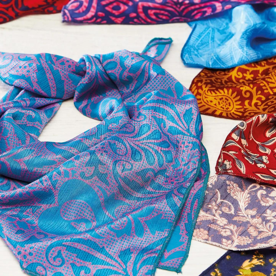 Colorful patterned fabric scarves on a white surface