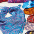 Colorful patterned fabric scarves on a white surface
