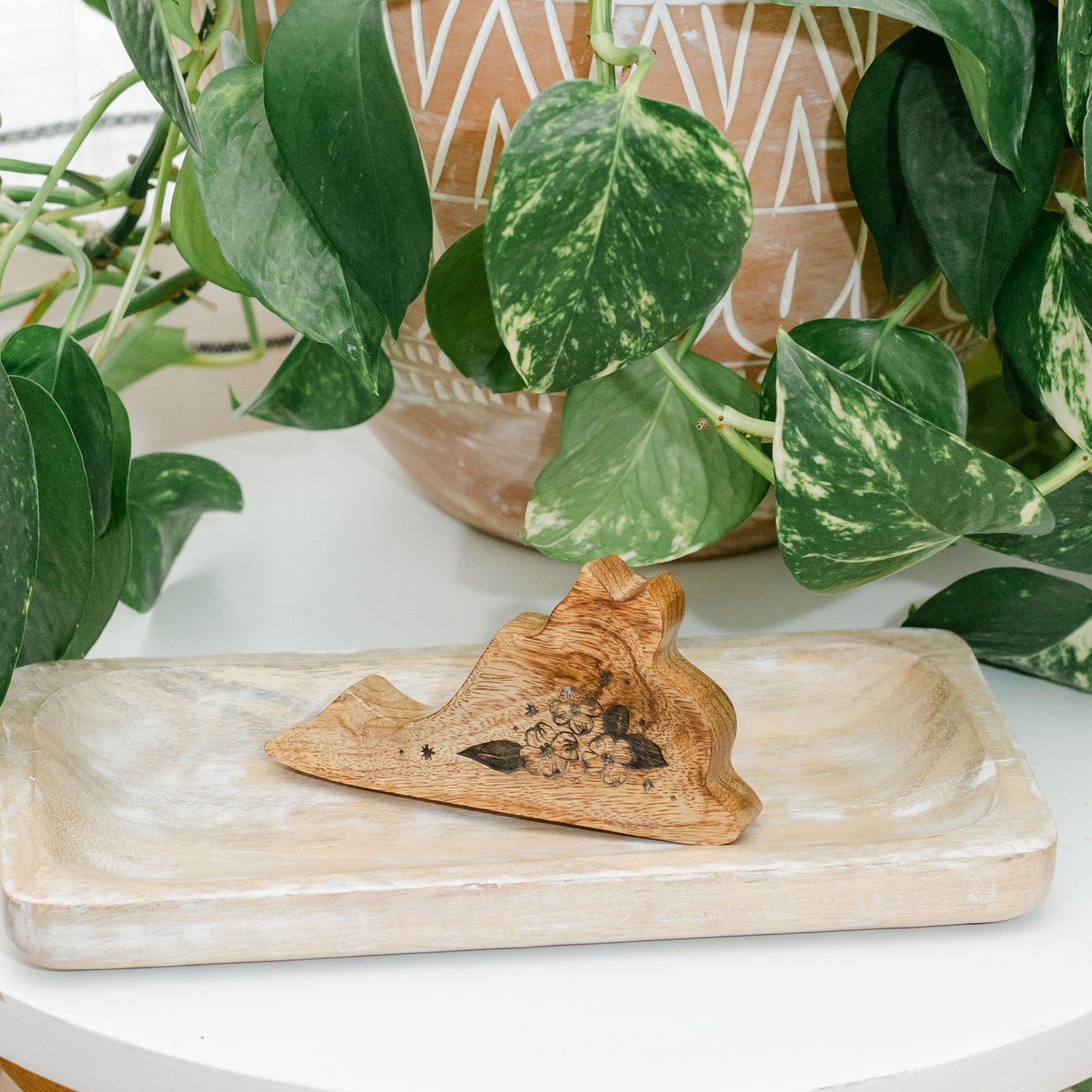 Wooden decorative dish in the shape of Virginia on a wooden tray with green leafy plants in the background