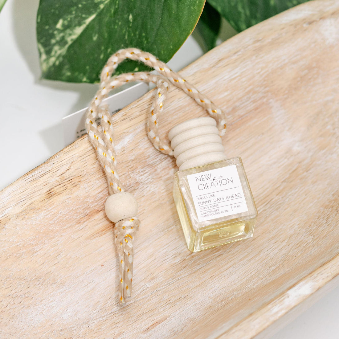 Car diffuser with packaging on a wooden surface with green leaves in the background