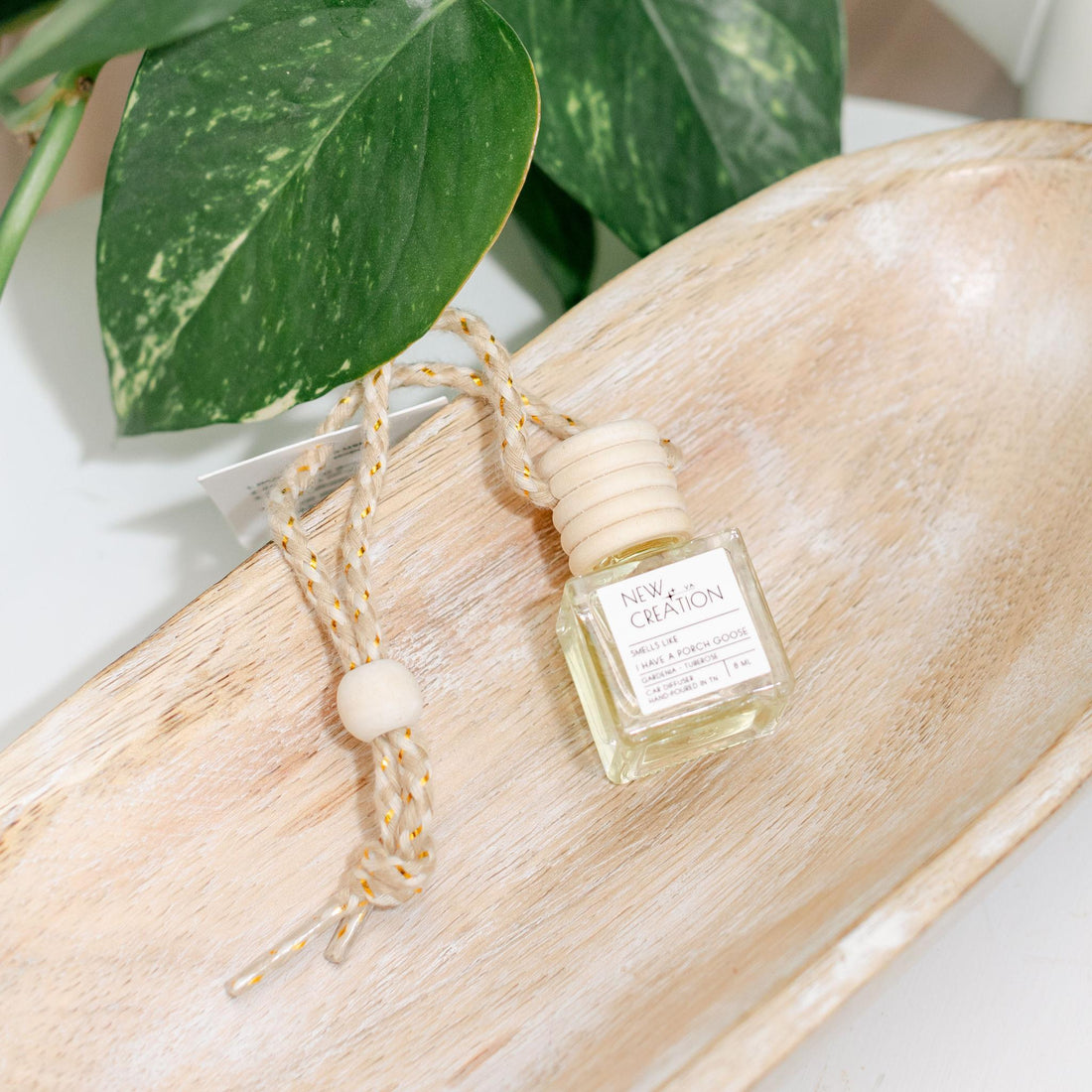Car diffuser with packaging on a wooden surface with green leaves in the background