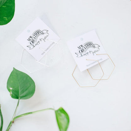 Two white cards with black text. Each card features a pair of thin hexagon hoops, one silver and one gold, on a light surface with green leaves.