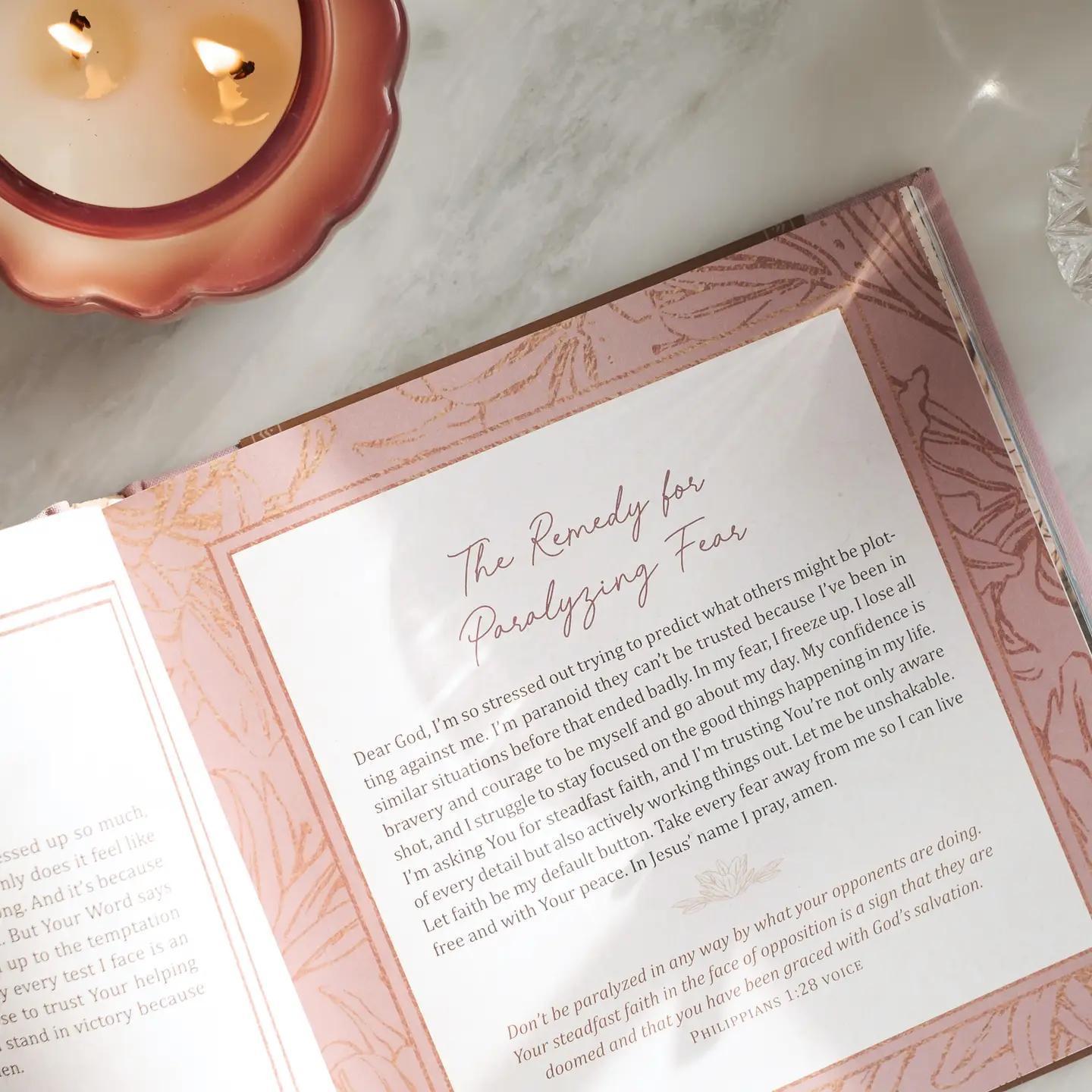 Open book with a letter on a marble surface next to a lit candle