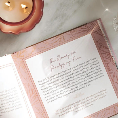 Open book with a letter on a marble surface next to a lit candle