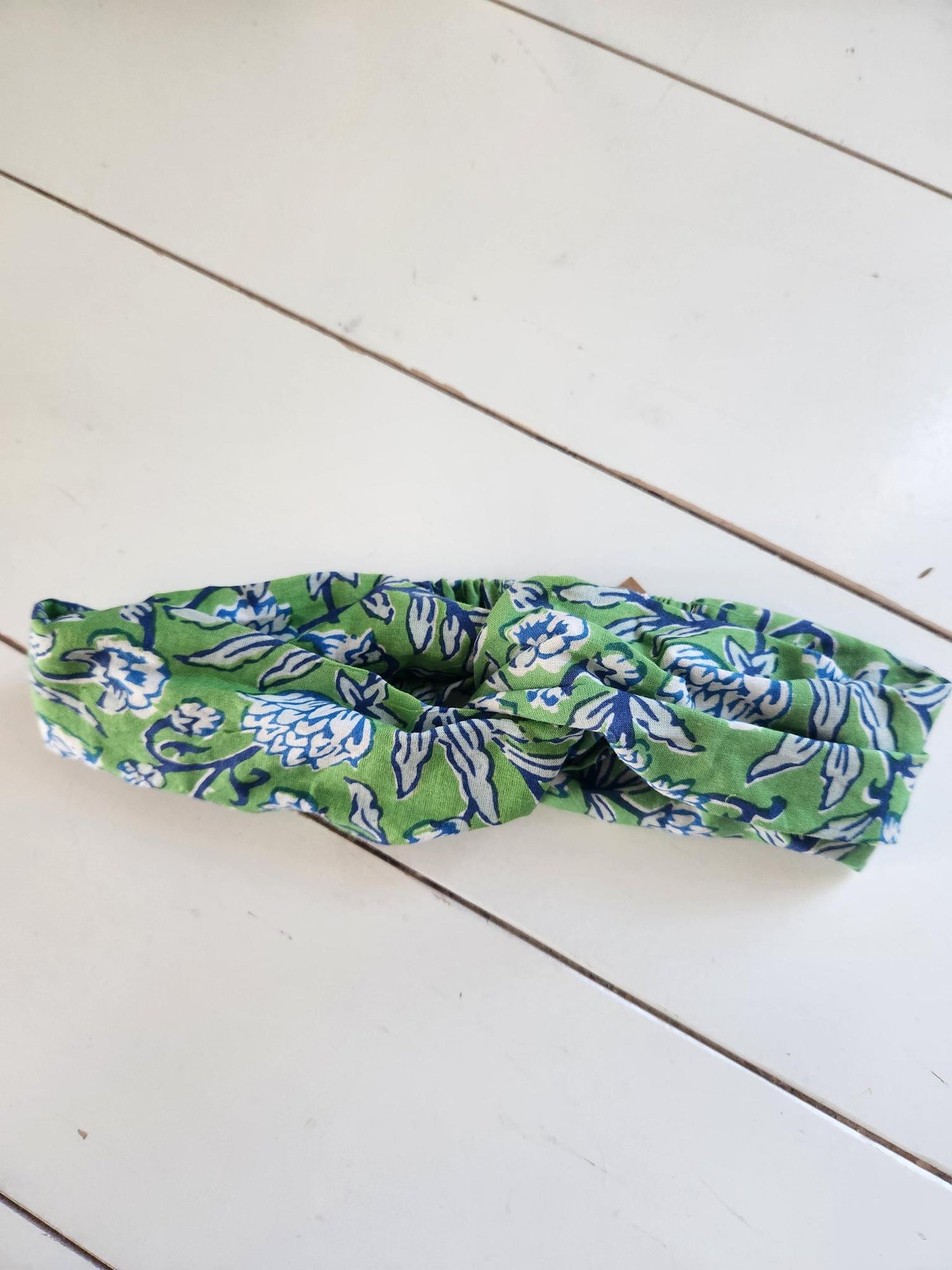 Green and blue patterned headband on a white wooden surface