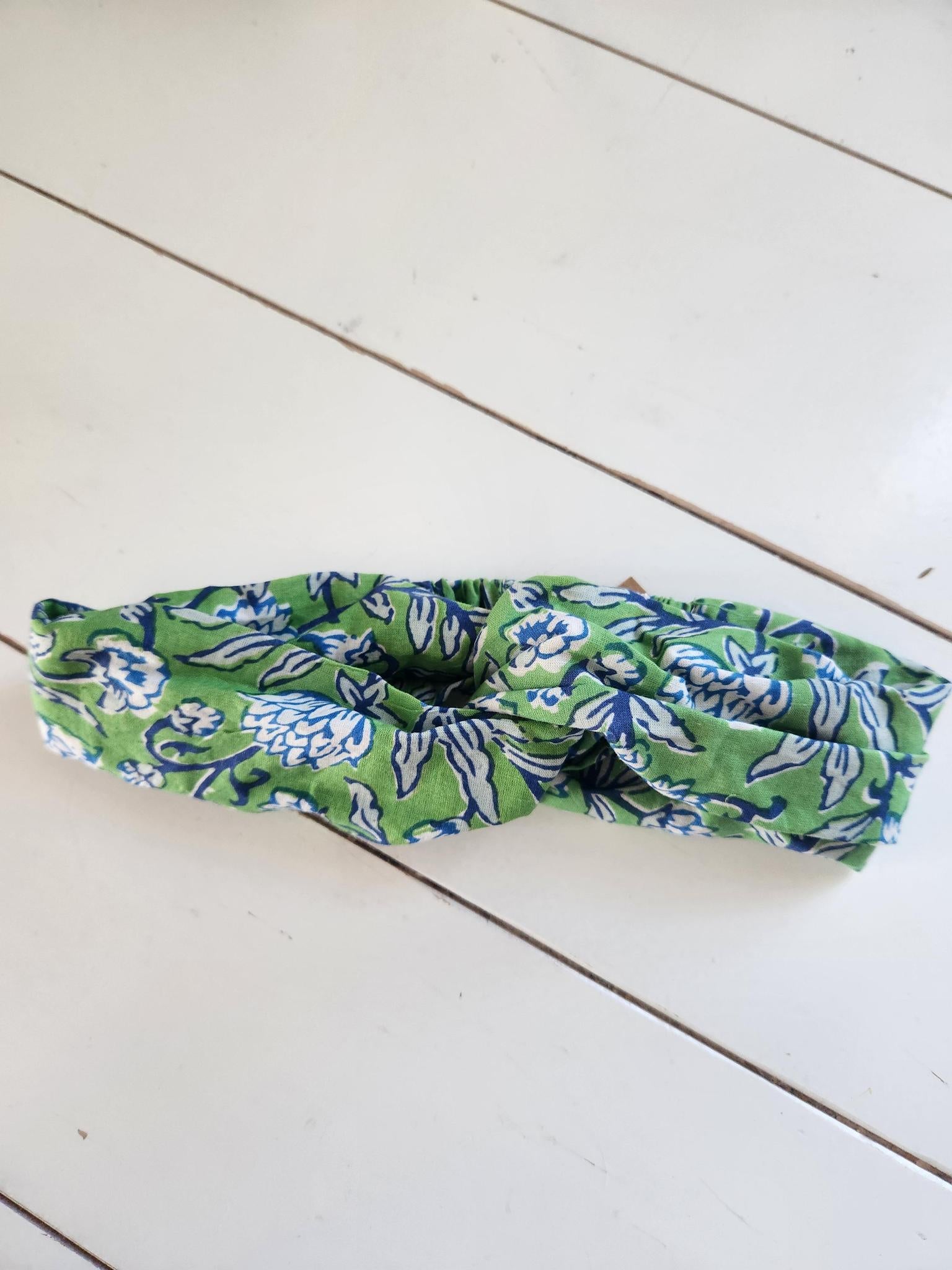 Green and blue patterned headband on a white wooden surface