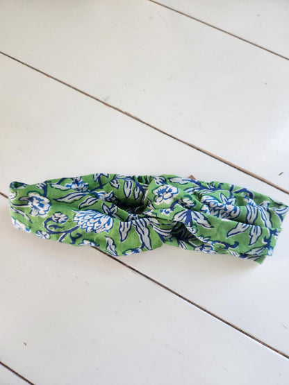 Green and blue patterned headband on a white wooden surface