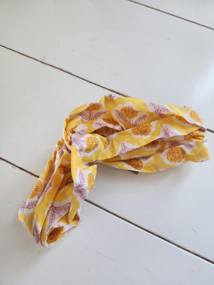 Yellow headband with floral pattern on a white wooden surface