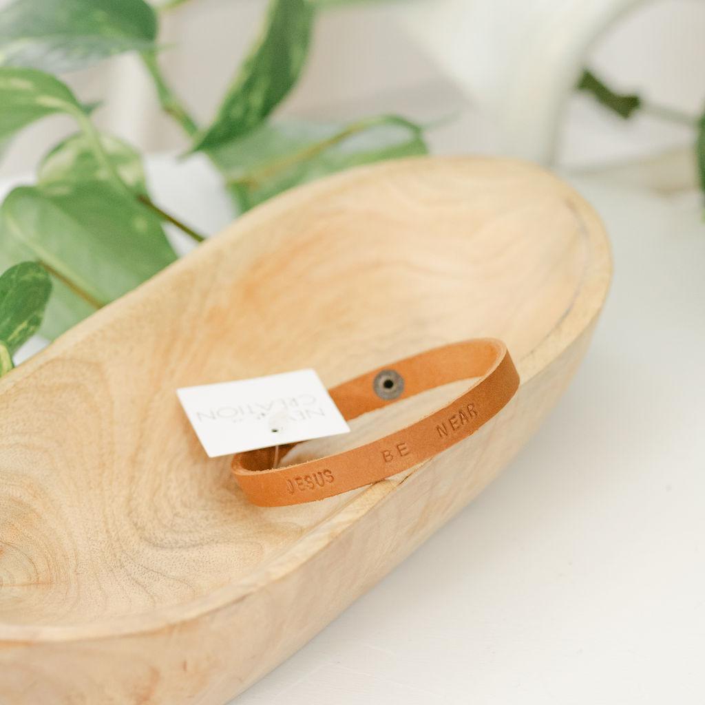 Close up of a light brown leather bracelet with &