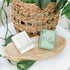 Silver hoop earrings displayed in a mint green jewelry box on a wooden tray, with another box beside it and a wicker basket with green leaves in the background.