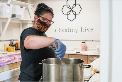 Woman wearing a face mask stirring a pot in a kitchen with &