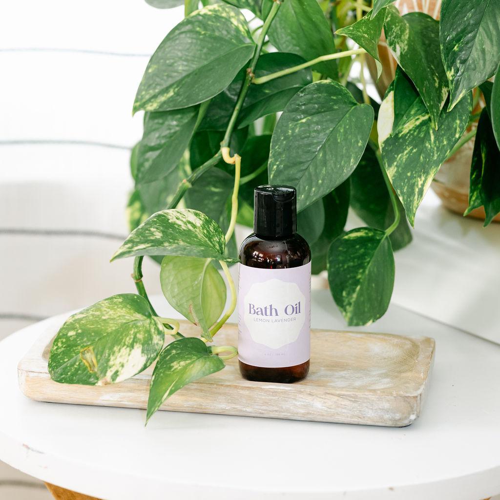Bottle of bath oil on a wooden tray with a plant in the background