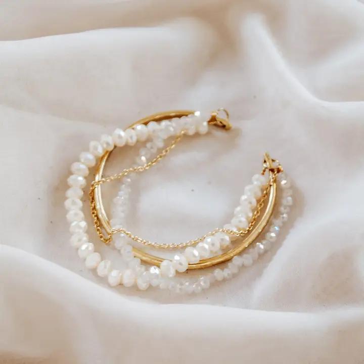 Pearl and gold cuff bracelet on a soft fabric background