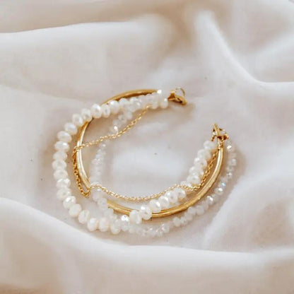 Pearl and gold cuff bracelet on a soft fabric background