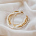 Pearl and gold cuff bracelet on a soft fabric background