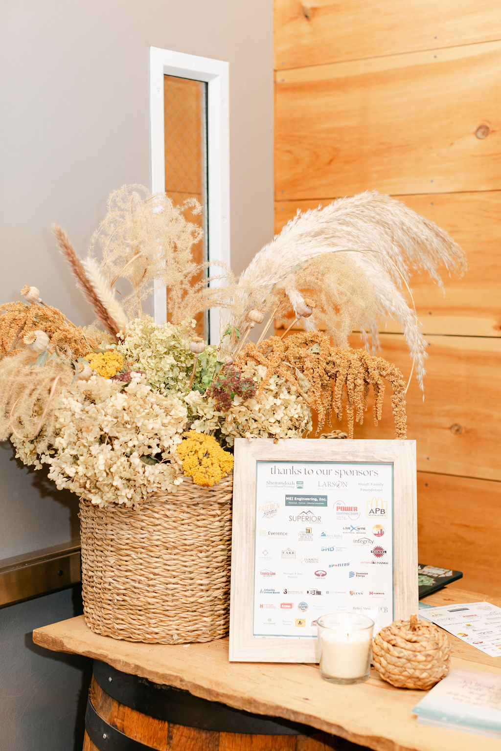 A floral display with a picture showing sponsors for a Night of Light event on a wooden table