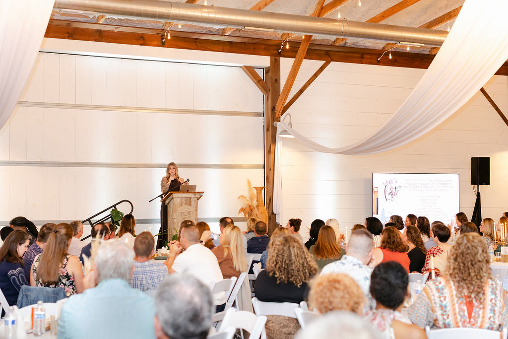 Audience attending a presentation in a modern indoor setting with wooden beams.