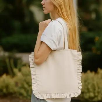 Woman holding a beige tote bag with ruffled edges outdoors.
