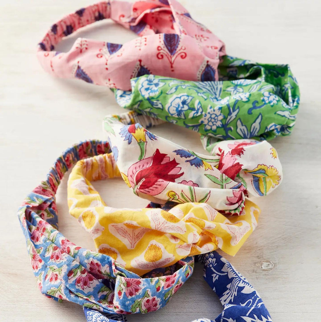 Colorful floral-patterned headbands on a light wooden surface