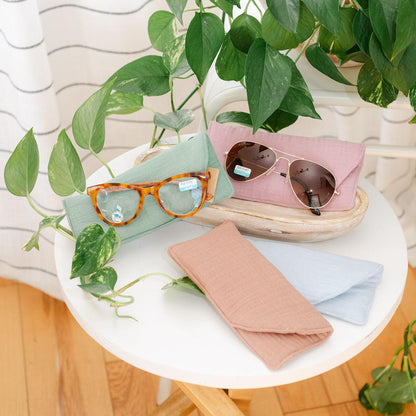 Sunglasses on cases on a table with greens in the background