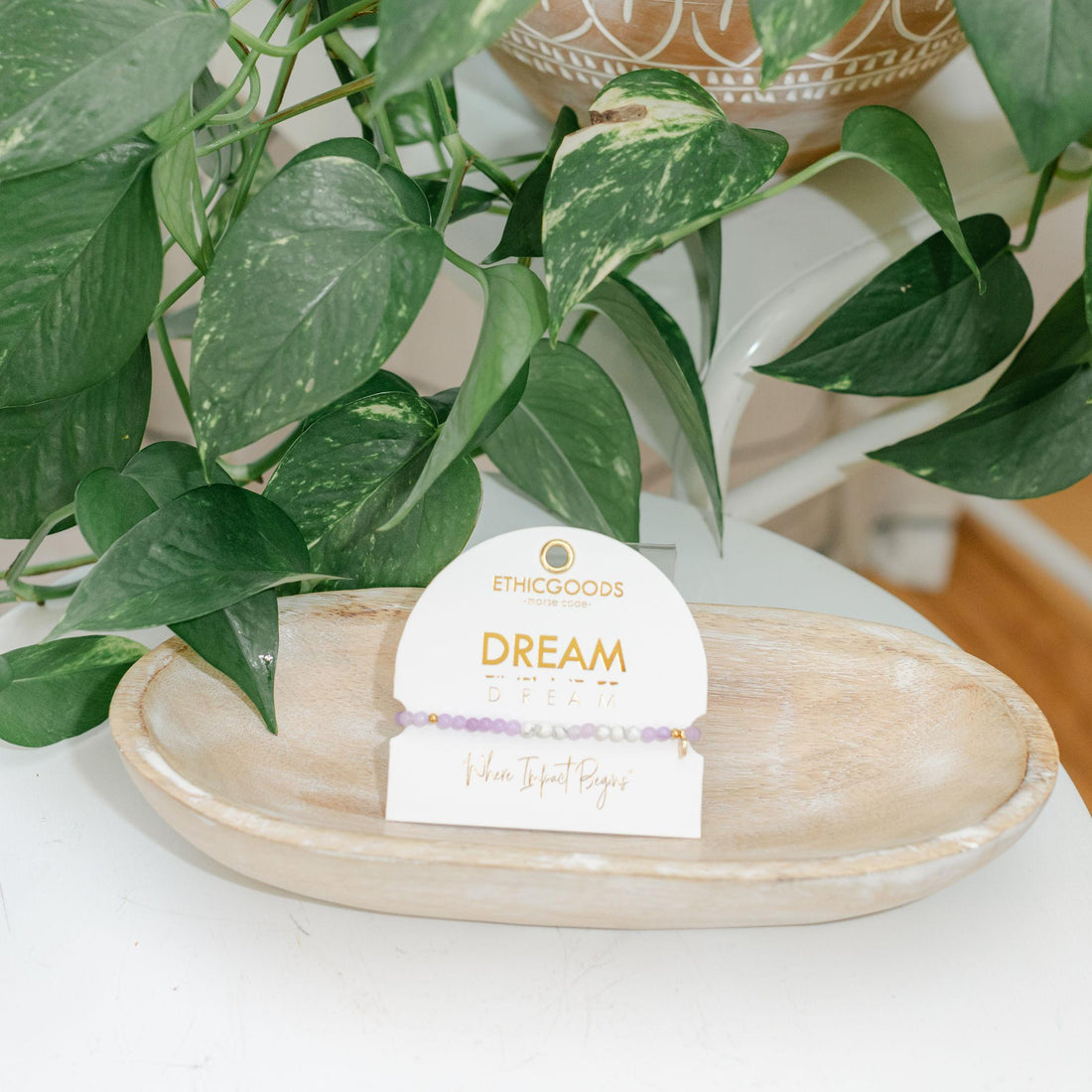 Potted plant on a white surface with an Ethicgoods product card showing &