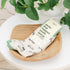 Pair of light green socks featuring bicycles with a packaging label on a wooden tray with a plant in the background