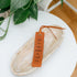 Leather bookmark with text on a wooden surface with a plant in the background