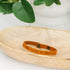 Light brown leather bracelet with For the Glory of God engraved sitting in a wooden dish
