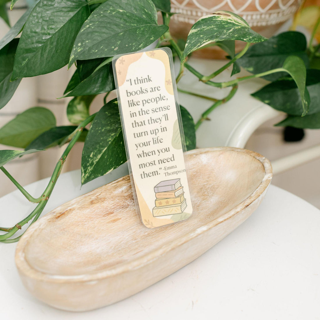 Bookmark with a quote on a wooden tray with plants in the background